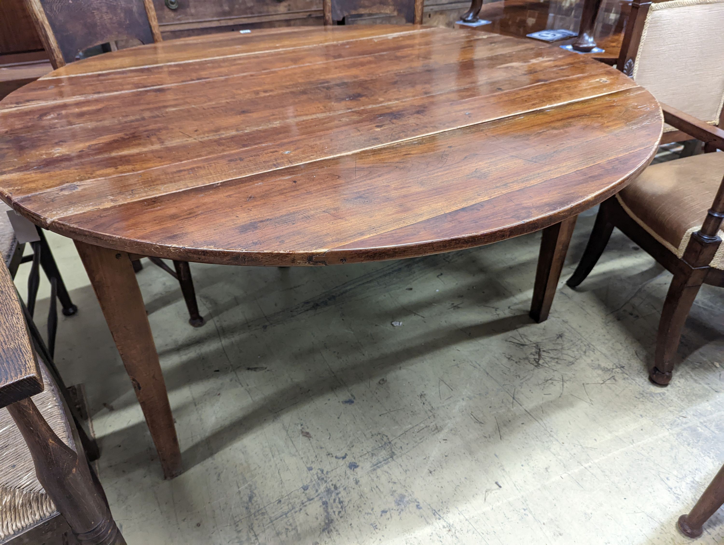A 19th century French fruitwood circular dropleaf dining table, length 145cm extended, width 144cm, height 73cm